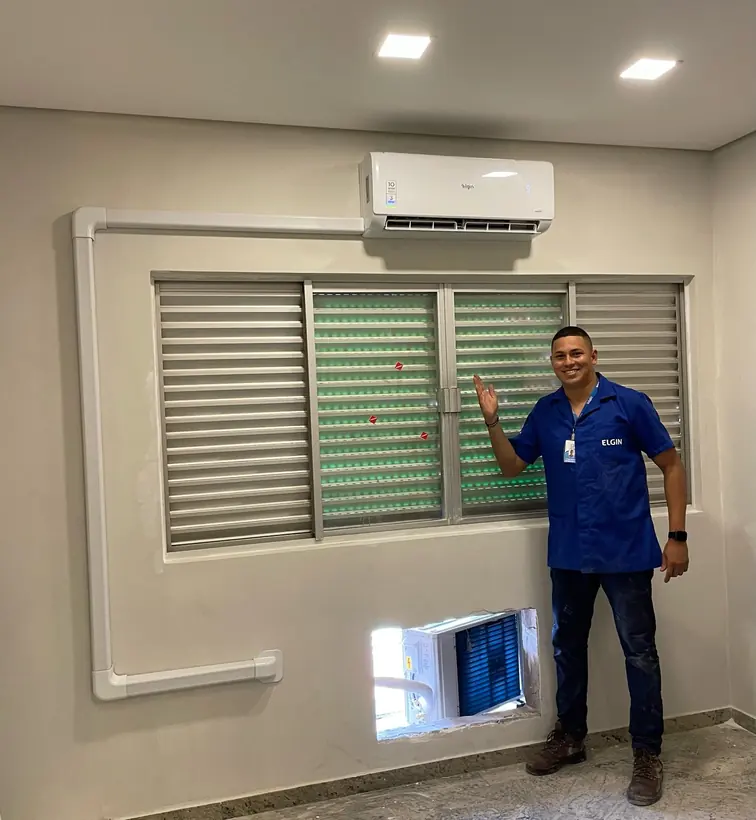 Técnico da TS ao lado de ar-condicionado instalado acima de uma janela